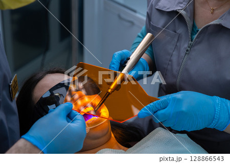 Dental Treatment in Progress: Patient Receiving Care with Advanced Dental Tools and Protective Equipment During Procedure for Cavity or Restoration Work to Ensure Oral Health 128866543