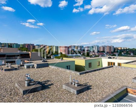 Aerial view of house flat roof on residental building. Modern architecture exterior. Air conditioning systems and ventilation structure. Residental building in background, sunny day Aerial view of house flat roof on residental building. Modern architecture exterior. Air conditioning systems and ventilation structure. Residental building in background, sunny day 128866656