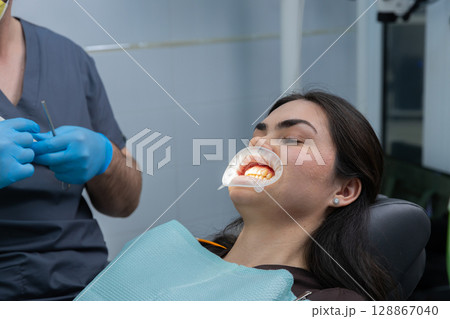 Dental Patient Undergoing Dental Consultation with Experienced Dentist in Clinic, Wearing Prophylactic Mouthguard for Oral Examination and Care Treatment in Modern Healthcare Setting 128867040