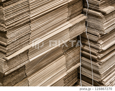 Stacks of cardboard sheets organized in a workshop for packaging and shipping materials near a busy urban area during daylight 128867270