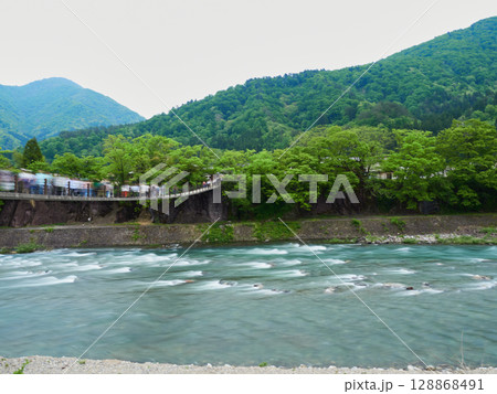 スローシャッターで撮影した夏の観光名所白川郷の出合い橋の観光客の姿 128868491