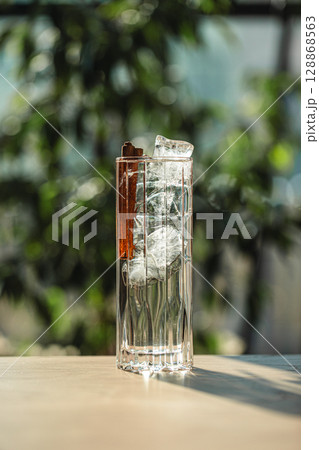 Crystal clear cocktail with ice cubes and cinnamon 128868563