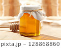 Honey Jar with a wood stick in a blurred background 128868860