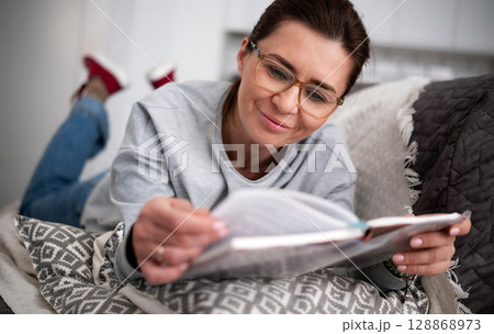 Happy Young Woman Reads An Interesting Modern Novel At Home 128868973