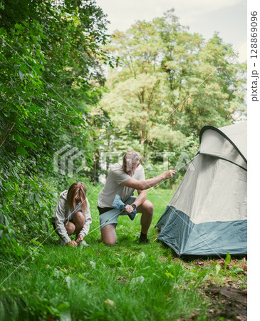 Father And Daughter Set Up A Tent At A Campground During Family Summer Camping Vacation Father And Daughter Set Up A Tent At A Campground During Family Summer Camping Vacation 128869096