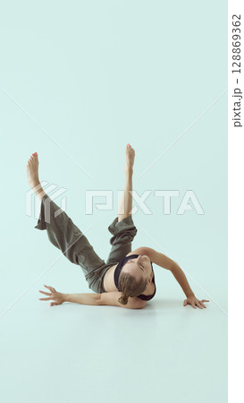 Graceful dancer extending both legs vertically in expressive floor pose with focus in contemporary performance Graceful dancer extending both legs vertically in expressive floor pose with focus in contemporary performance 128869362