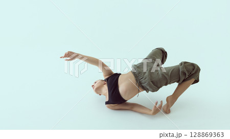 Contemporary dancer twisting on floor with extended arm and emotional upward gaze 128869363