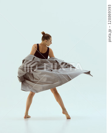 Fashionable dancer spinning in oversized coat mid-turn with playful confident motion Fashionable dancer spinning in oversized coat mid-turn with playful confident motion 128869393