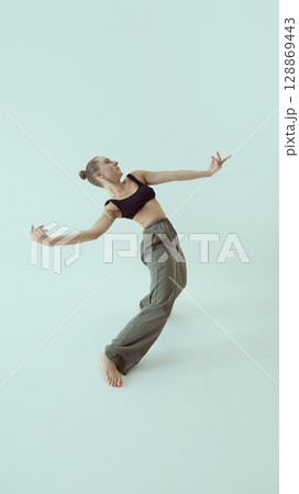 Fashionable model leaning backward in expressive open-arm pose with emotional intensity 128869443