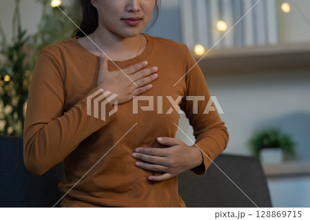 Health Awareness: Young woman feeling abdominal discomfort at home Health Awareness: Young woman feeling abdominal discomfort at home 128869715