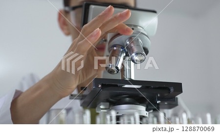 Female scientist analyzing test samples under microscope in contemporary research environment of laboratory. Medicine, healthcare and science concept Female scientist analyzing test samples under microscope in contemporary research environment of laboratory. Medicine, healthcare and science concept 128870069
