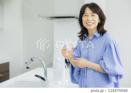 キッチンで水を飲む女性  128870086