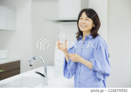 キッチンで水を飲む女性  128870092