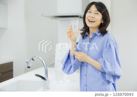キッチンで水を飲む女性  128870093