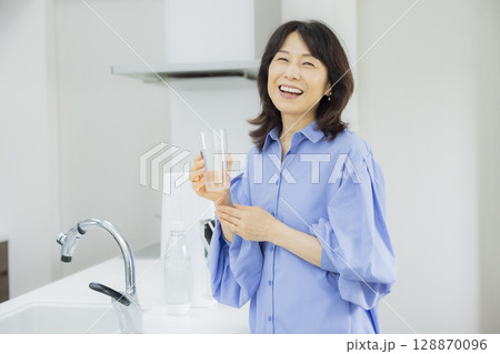 キッチンで水を飲む女性  128870096