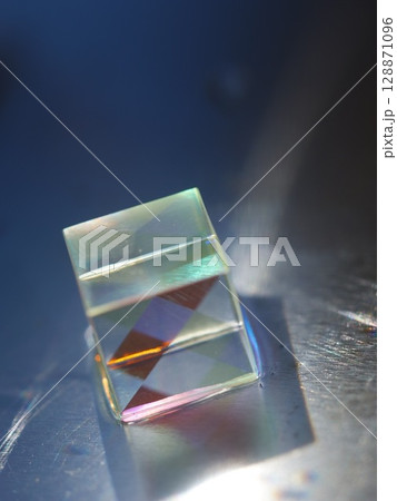 Small cube of glass with a rainbow pattern on it 128871096