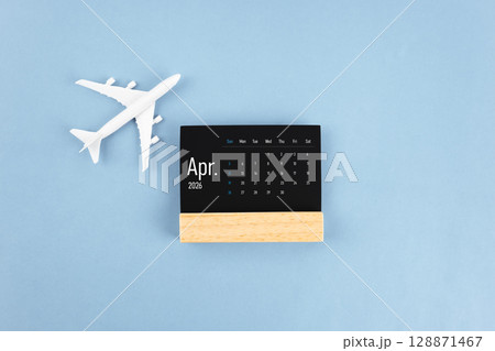April 2026 black wooden calendar and airplane toy on blue color background. 128871467