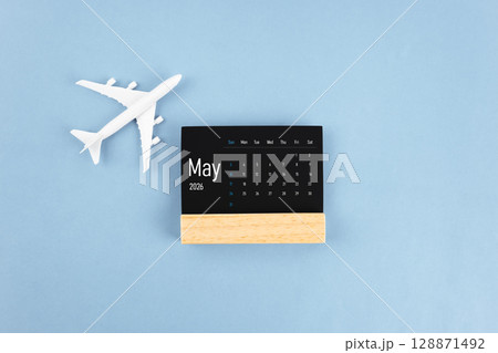 May 2026 black wooden calendar and airplane toy on blue color background. 128871492