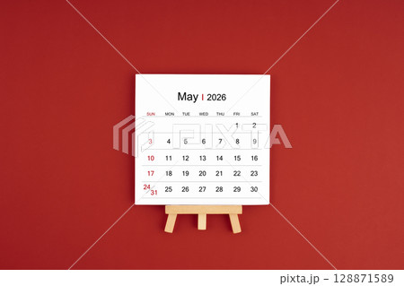 Calendar page for May 2026 with wood easel on a dark red background. Calendar page for May 2026 with wood easel on a dark red background. 128871589