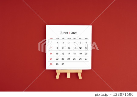 Calendar page for June 2026 with wood easel on a dark red background. 128871590