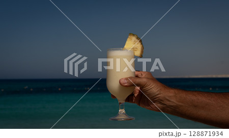 man drinking glass of pina colada on beach 128871934