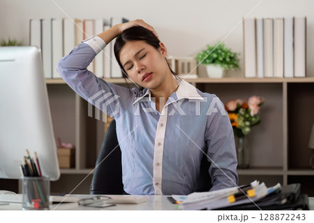 Office Syndrome: Woman stretching neck to relieve tension at her desk 128872243