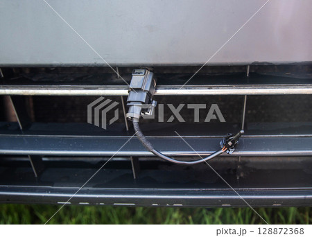 Black car outside air temperature sensor against the background of a car bumper grille. Measuring air temperature, close-up 128872368