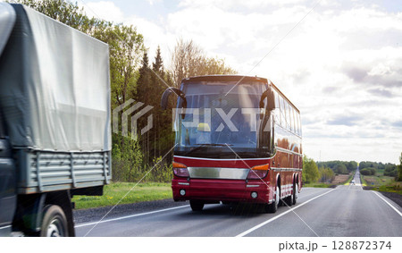 A modern passenger bus carries passengers outside the city on a summer trip. Against the backdrop of a cloudy sky and the sun. Copy space for text, comfortable 128872374