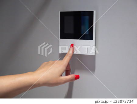 A woman's hand with a red manicure opens the front door in an electronic video intercom, close-up. Copy space for text A woman's hand with a red manicure opens the front door in an electronic video intercom, close-up. Copy space for text 128872734