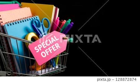 Shopping cart with school supplies and Special Offer tag. Back-to-school deals and savings. 128872874