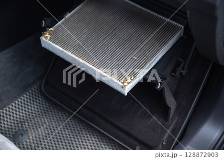 Old dirty carbon cabin filter of the car. Concept of replacement with a new one. Cleaning the air in the car cabin, close-up 128872903