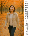 紅葉の並木道を歩く中高年女性・健康的な秋のライフスタイル 128873524
