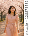 満開の桜の下を歩く女性・春のやわらかな日差しと微笑み 128873532