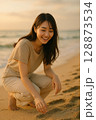 夕暮れの海辺で微笑む若い女性・穏やかなひととき 128873534