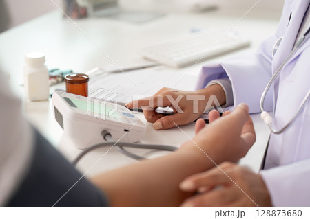 Patient Care. Doctor measuring blood pressure in medical consultation. Patient Care. Doctor measuring blood pressure in medical consultation. 128873680
