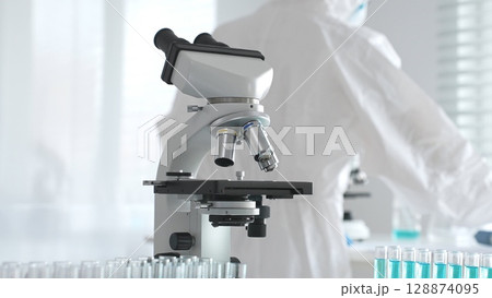 Modern microscopes and test tubes containing blue liquid are arranged on a table in a bright laboratory setting, ready for scientific research and analysis Modern microscopes and test tubes containing blue liquid are arranged on a table in a bright laboratory setting, ready for scientific research and analysis 128874095