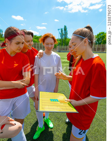 Female soccer team planning on athletic field beneath sunny sky Female soccer team planning on athletic field beneath sunny sky 128876073