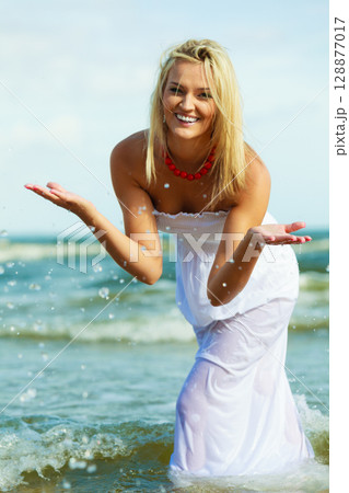 Blonde woman wearing dress playing with water 128877017