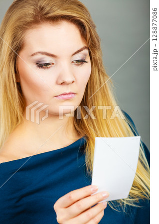 Seriously worried woman looking at piece of paper 128877086