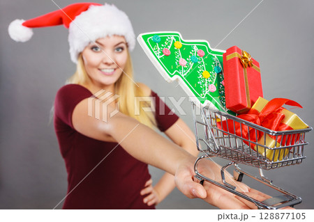 Santa woman holding shopping cart with christmas gifts Santa woman holding shopping cart with christmas gifts 128877105