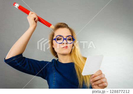 Confused woman holds big pencil note paper in hand 128877212