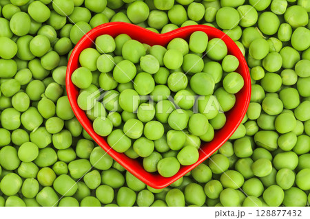 Fresh green peas in red ceramic bowl as a background. Top view. Flat lay Fresh green peas in red ceramic bowl as a background. Top view. Flat lay 128877432