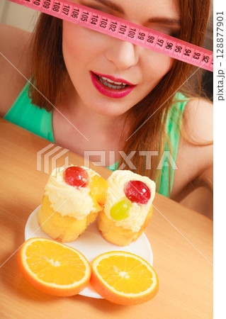 Woman with tape measure and cake. Diet dilemma. 128877901