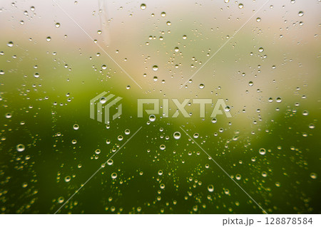 Close-up of water droplets on glass with blurred green background  128878584