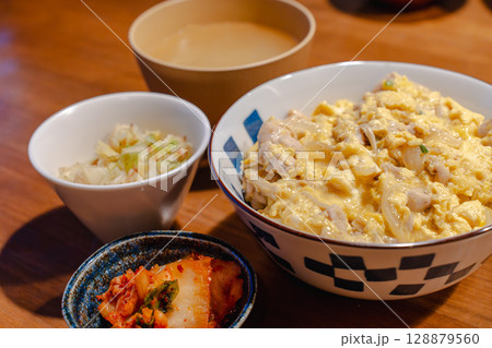 親子丼と味噌汁が並ぶ和風の家庭的な夕食 128879560