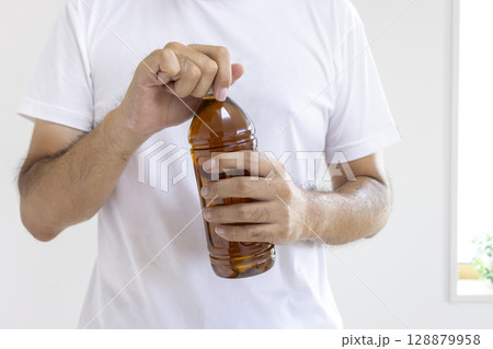 ペットボトルを開けている男性(日本人、30代、顔無し) ペットボトルを開けている男性(日本人、30代、顔無し) 128879958