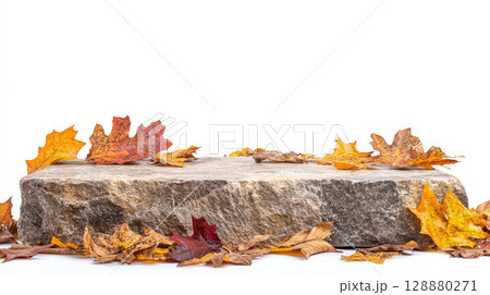 rustic stone podium is adorned with vibrant autumn leaves, creating natural display against clean white background. earthy tones evoke warm and seasonal atmosphere. 128880271