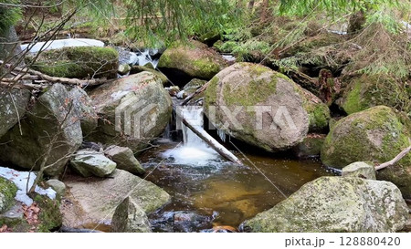 A Tranquil Stream Gently Flowing Over Smooth Rocks in a Beautiful Natural Landscape 128880420