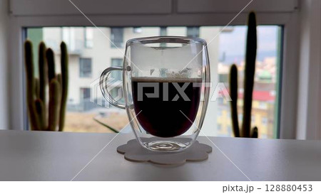 A delightful cup of coffee in a stylish glass, set against a vibrant urban backdrop 128880453