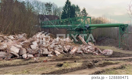 A collapsed industrial structure surrounded by debris and heavy machinery scattered everywhere 128880471